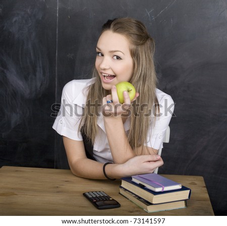 portrait of happy cute young student near blackboard with copy book calculator pen, copy space