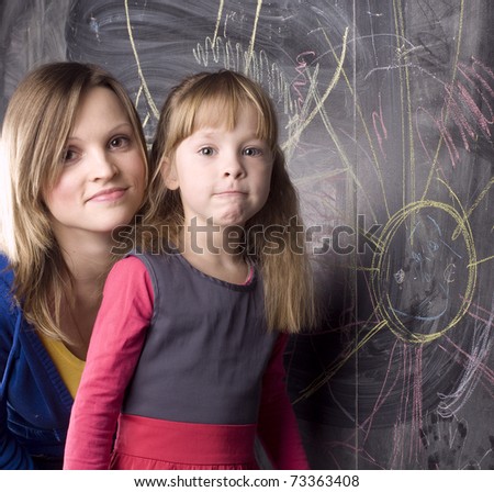 portrait of mother and daughter near blackboard, teaching process