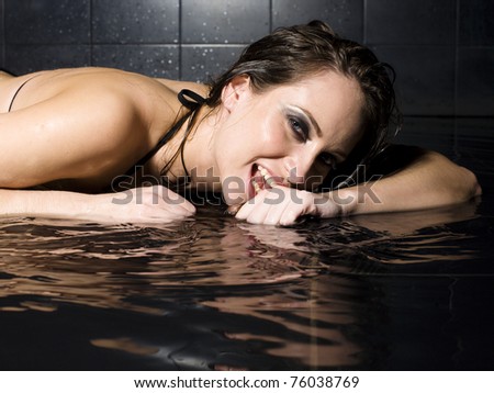 portrait of pretty sexy lady in water, black bathroom