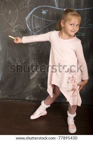 portrait of little cute girl with chalk writing on blackboard