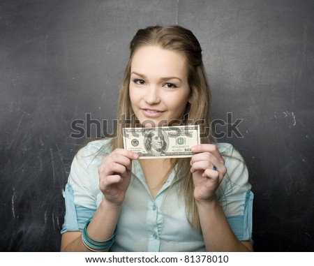 portrait of happy cute student with money, near blackboard