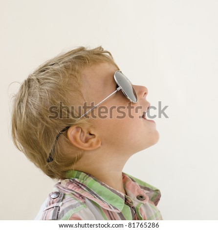Little boy in sunglasses with money smiling, against white background