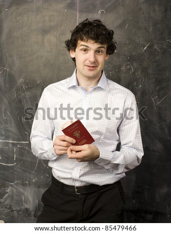 portrait of man student with money and passport, standing at blackboard