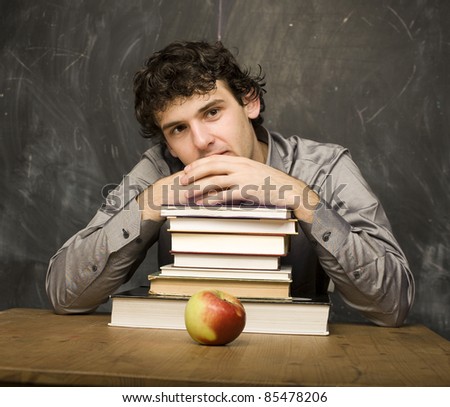 The young emotional student with the books and red apple in class room, at blackboard