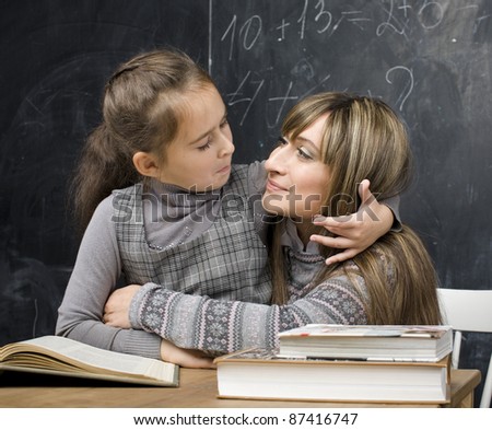 portrait of little girl with teacher in classroom near black board