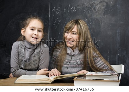 portrait of little girl with teacher in classroom near black board
