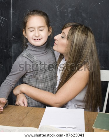 portrait of little girl with mother hugging at blackboard, making lessons