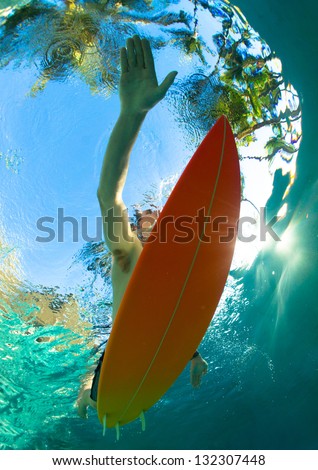 Young surfer paddling through the ocean