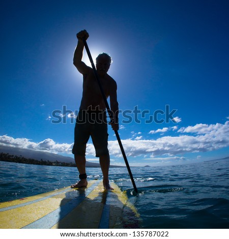 Stand Up Paddle Boarder Exercising In The Ocean