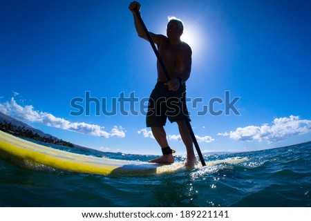 Stand up paddle boarder paddling off the coast of Maui, Hawaii