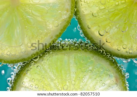 Sublime - Three slices of lime in soda water against an ultramarine blue background