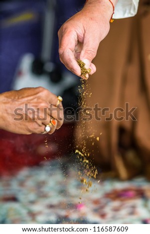 In Haldi ceremony, which is celebrated the day before the indian wedding ceremony, two hands is sprinlking turmeric powder