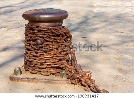 Old mooring bollard with a rusty chain.