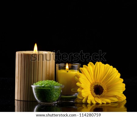 aromatherapy with candles green sea salt and yellow flower on dark background