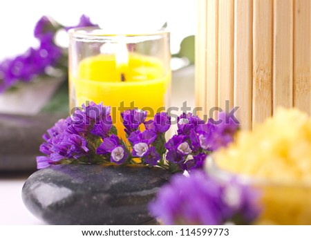 Spa still life with  candles, flower, towel and stones on orange background