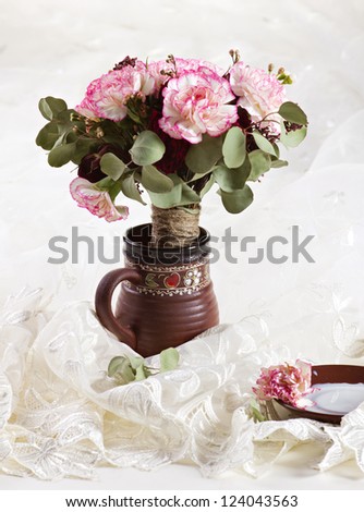 bouquet of flowers  in a jug and saucer with milk on silk textile and unfocused background