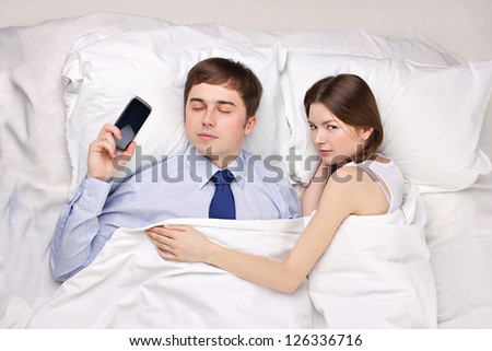 man obsessed by work in bed with woman