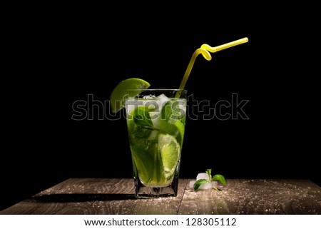 fresh cocktail with citrus fruit, mint and ice on wooden table on black background