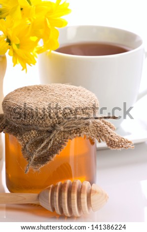 closeup of honey,  tea in teacup and yellow flowers  on white background
