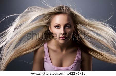 portrait of a girl with blond long waving hair on gray background
