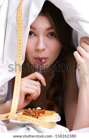 young beautiful woman under white cover eating cake, near - measure