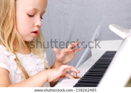 Little Blond Girl In Beautiful White Dress Playing On White Piano, Closeup