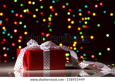 christmas surprise - gift box with silk bow on colorful bokeh background