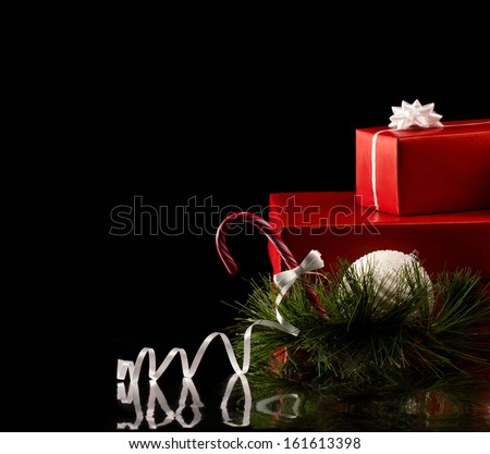 christmas card with gift red boxes, white ball and bow and green branch of fir tree on black background