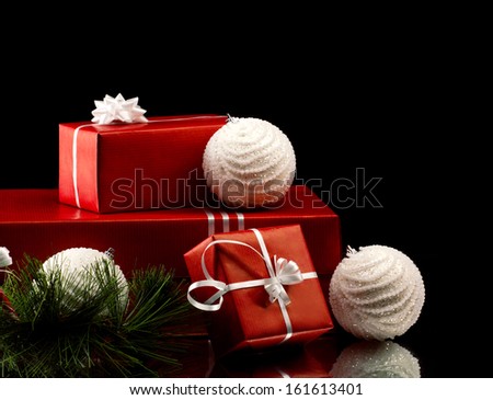 christmas gift red boxes with silver bright bow, branch of firtree and white balls on black background