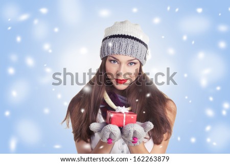 young woman in hat and gloves with  gift red box on blue and snow background