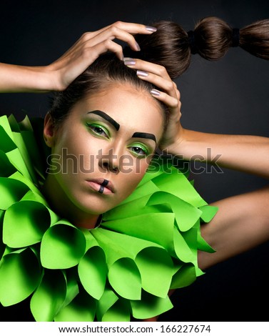 closeup portrait of a fashion woman with green visage and creative coiffure on dark background