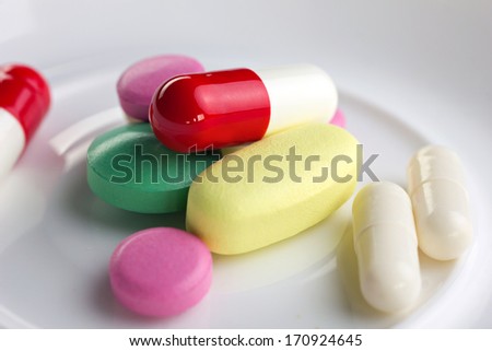close-up pharmaceutical colorful tablet and capsule on white plate