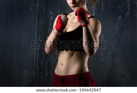 Sexy woman boxer in red and black clothes  ready to fight  on grunge dark grey background