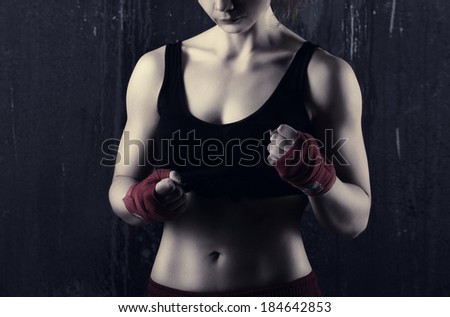 young woman boxer in red and black clothes  ready to fight  on dark grey background