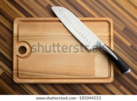 big steel knife and wooden  carving board on wooden background