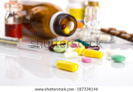drug in yellow capsule on white table and blurred background with different medicament in blisters and bottle and thermometer