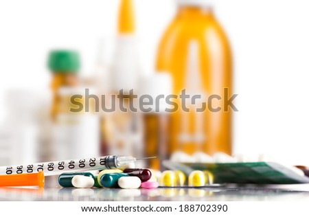 insulin syringe and different medicament in on blurred bottles and white background