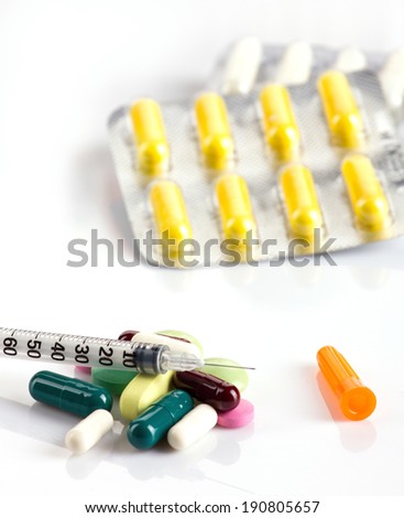 colorful medicaments in tablets  and capsules and insulin syringe on white background