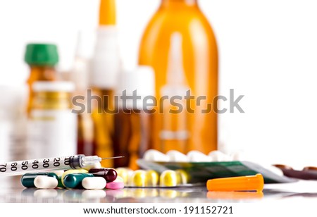 colorful medicaments in tablets  and capsules, insulin syringe and different glass bottles on white background