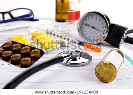 insulin syringe, different medicaments, doctor\'s stethoscope and glasses on medical form on white background