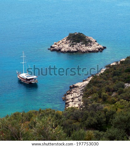 Blue and turquoise sea,  rocky beach with green vegetation, little island and  sailing, Turkey, kaputas beach