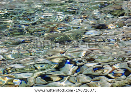 Pebbles under colorful transparent water, abstract   surface  texture