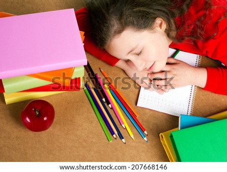 little girl sitting  at the table with school accessories and red apple and sleep, top view