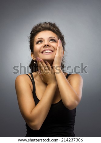portrait of a happy young woman in black shirt looking up on grey light background