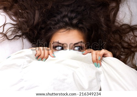 young shocking  woman with beautiful brown  dishevelled curls hair in the bed