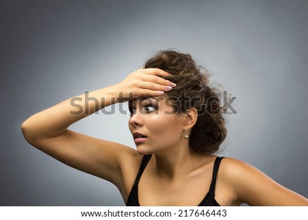 stressed young brunette woman holding her head, isolated on grey light background