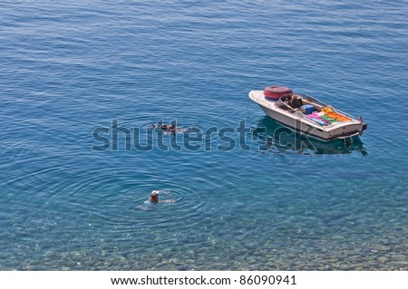 couple swimming in the sea, close to the boat