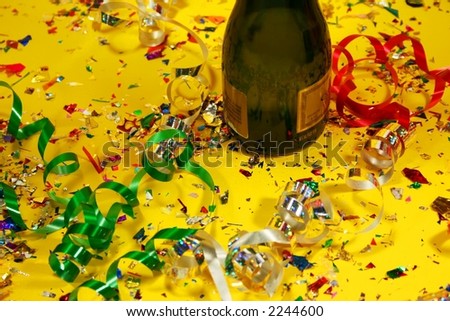 A champagne bottle surrounded by confetti and ribbon.
