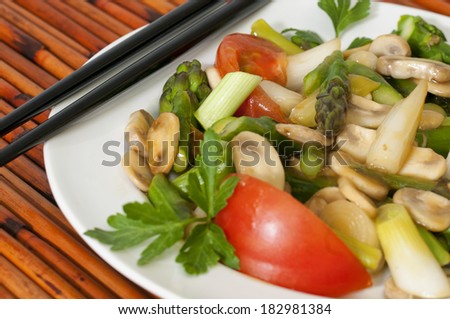 A plate of asparagus & vegetable stir fry against a bamboo place mat