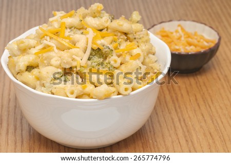 Macaroni and cheese casserole with a small side bowl of cheddar cheese to add, out of focus to leave attention on the large bowl